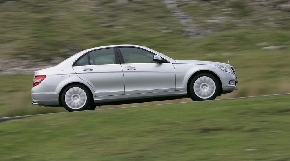 Side profile of silver sedan driving with motion blur