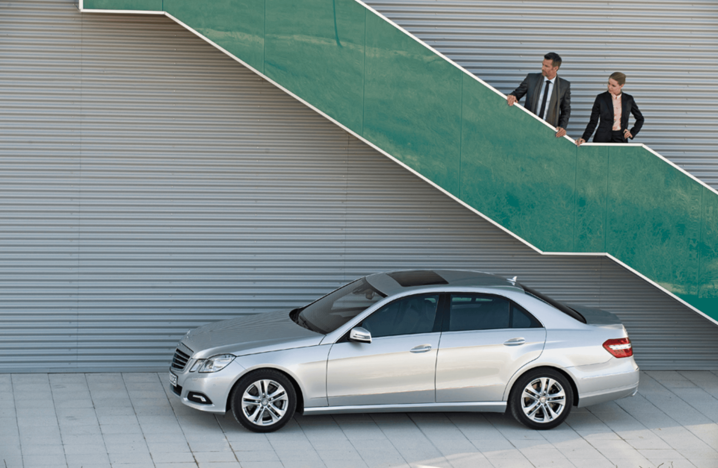 Silver sedan side profile parked beneath green architectural stairs